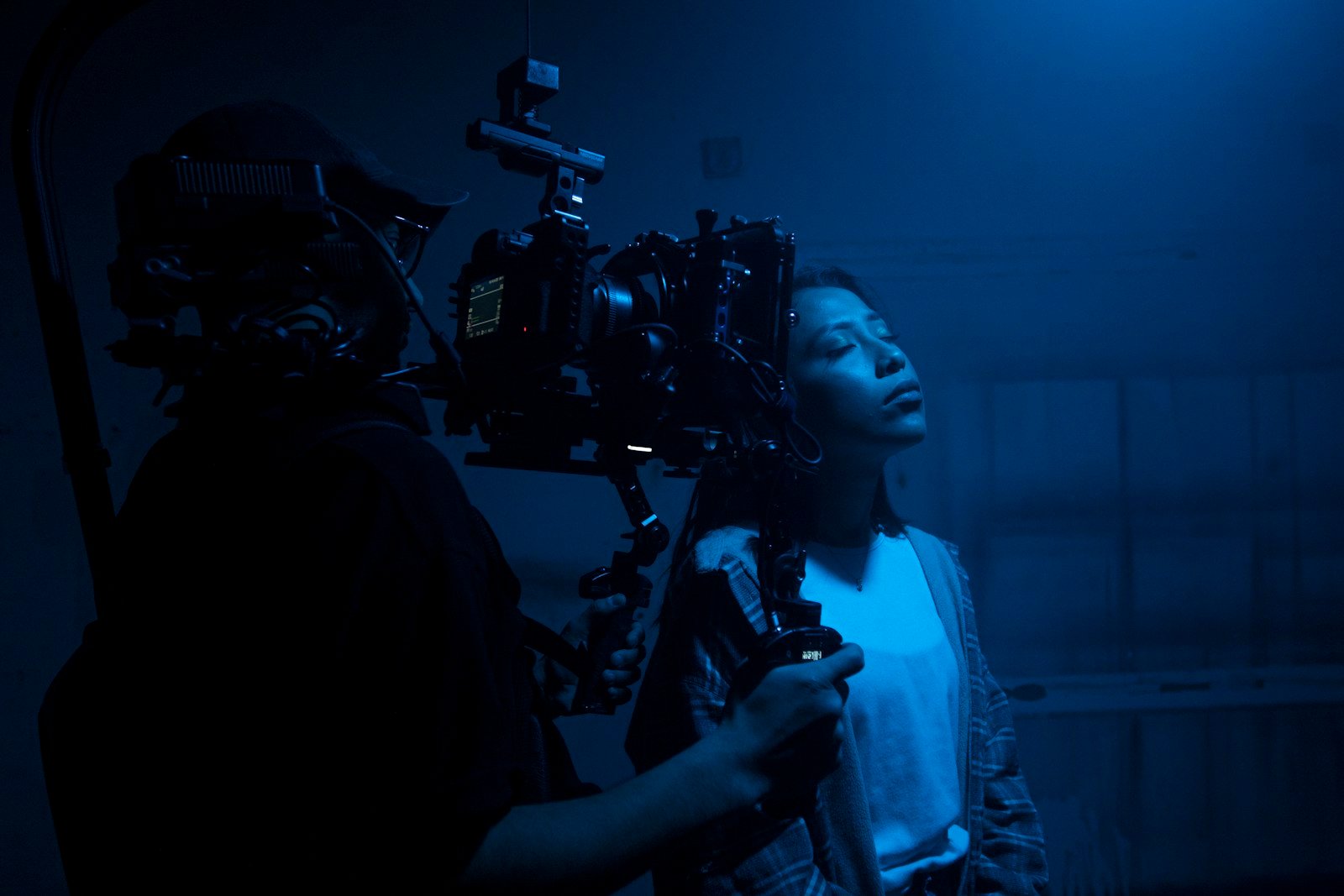 A woman standing beside a man holding a camera, looking at it together
